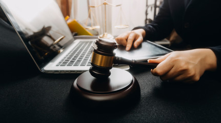 Justice and law concept.Male judge in a courtroom with the gavel, working with, computer and docking keyboard, eyeglasses, on table in morning ligh