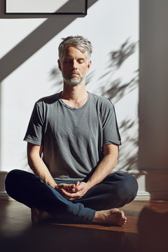 Mature man sitting on the floor at home meditating