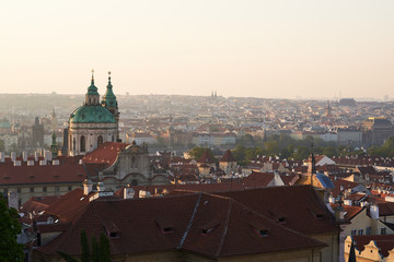 Cityscape picture of Prague, capitol of Czech republic taken from prague castle. Main subject is tower of Saint Nicolas church in Lesser town. Picture is taken in golden hour just after sunrise.