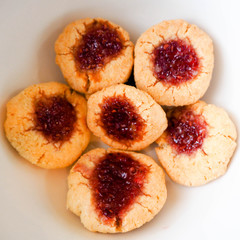 six round little coconut cookies made from rice flour, topped with red raspberry jam. gluten-free baking at home