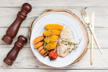 Grilled chicken breast with pumpkin, pepper, carrot and herbs. Healthy food concept. Wooden background.