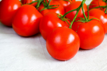 close-up of red round tomatoes on a white linen surface. raw red vegetables