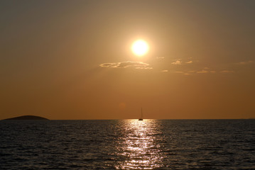 small island, sunset and sailing yacht in the Mediterranean sea