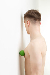Naklejka premium Handsome man shows exercises using the mini fitness ball