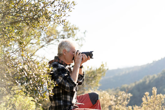 Senior man photographing in nature