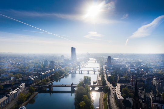 Germany, Hesse, Frankfurt, Helicopter view of sun shining over river Main and surrounding city buildings