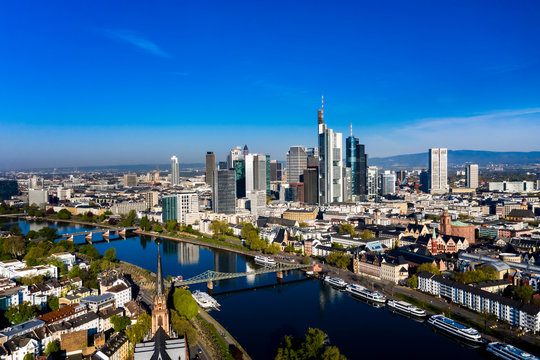 Germany, Hesse, Frankfurt, Helicopter view of riverside city with downtown skyscrapers in background