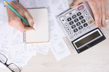 Unrecognizable businessman using calculator on desk office and writing make note with calculate...