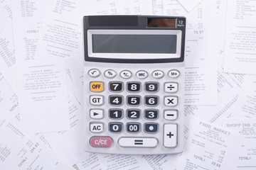 Calculator for counting on a pile of checks from purchases from the store on a wooden background. Top view. Place for text.Copy space