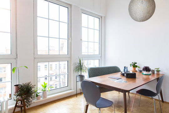 Dining table in bright living room with large windows