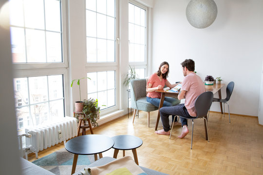 Couple sitting at table at home talking