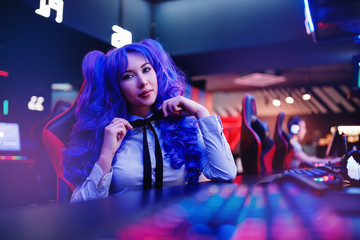 Woman gamer sitting table, playing online games on computer, neon color