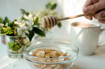 Mini cereal pancakes, Little dutch poffertjes. woman pouring honey on pancakes. little pancakes in transparent bowl and coffee cup. top view. New trendy breakfast in social media. Funny food for kids 