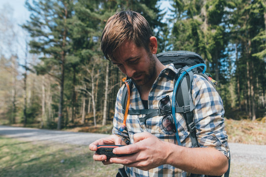 Young man checking navigation device in forest