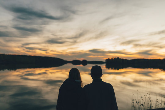 Couple sitting at lake, watching sunset