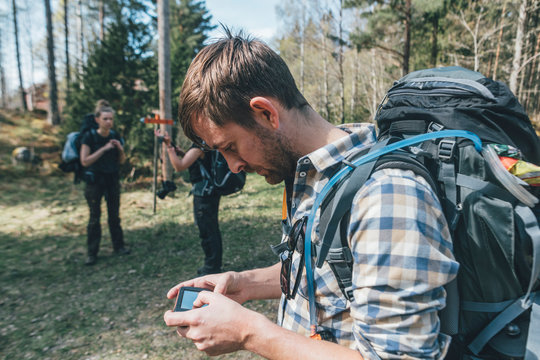 Young man checking navigation device in forest