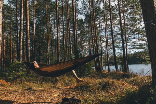 Young amn relaxing in hammock at lake
