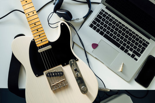 Top view of electric guitar, laptop, smartphone and headphones