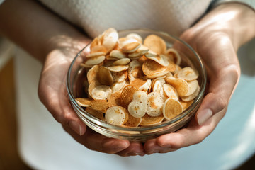young woman holding mini cereal pancakes, Little dutch poffertjes. little round pancakes in transparent bowl on grey background. New trendy dessert in social media. Funny food for kids 