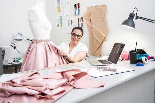 Seamstress working in tailor shop and presenting skirt via video call
