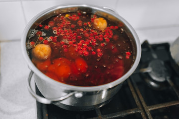 Cooking a delicious compote of apricot, apples, cherries, raspberries. Fresh fruits are boiled in boiling water in a metal pan on the stove. Photography, concept.
