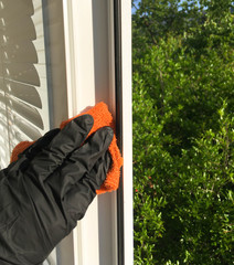 A hand in a black glove wipes the windows with a napkin. Washing dirty window washers in summer.