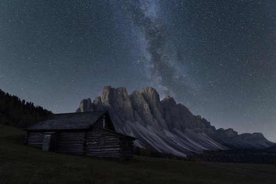 View of milky way over Odle mountain range and hut at night