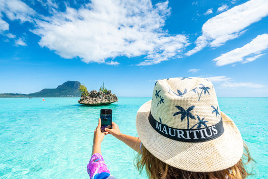 Woman photographing the tropical lagoon and Crystal Rock with smartphone, La Gaulette, Le Morne Brabant, Mauritius, Indian Ocean, Africa