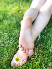 Barefoot kid lying on green grass against blurred background. Having fun outdoors in spring park