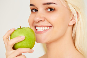 Woman with Apple. Beautiful girl close up with white smile on a gray background, healthy teeth. High Resolution Image