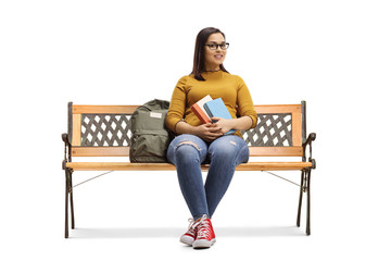 Female student sitting on a bench and holding books