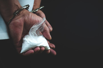 drug addict in handcuffs with a package of drugs in his hands