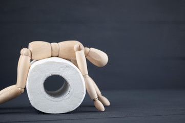 wooden mannequin and toilet paper on a black background