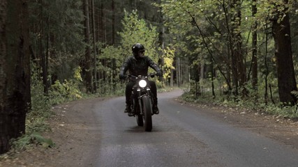 Guy riding motorcycle on forest road