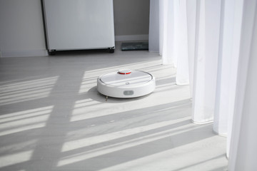 Robot vacuum cleaner cleans on a bright floor.