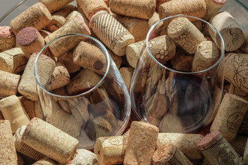 Two wine glasses with red wine among wine corks. Reflection of corks in wine.