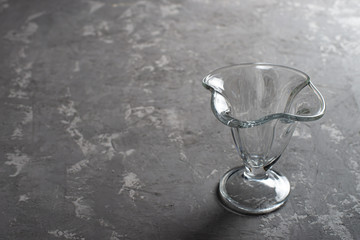 Empty glass ice cream bowl on a dark concrete background. Dessert cup