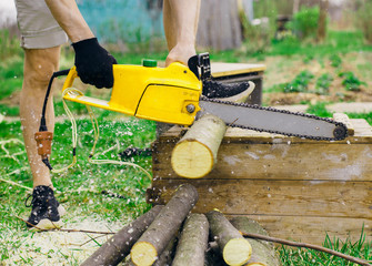 Chainsaw work in the backyard of house.  Closeup of instrument and hands.