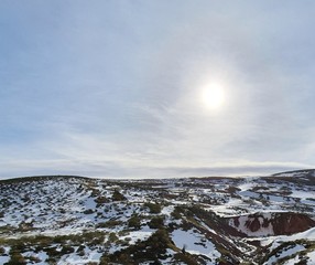 a cold evening in a snowy tundra mountains with the sun in the sky
