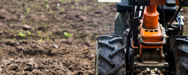 Motorcycle cultivator against the background of plowed beds in the garden