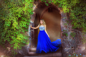 young girl in a blue dress near the green arch