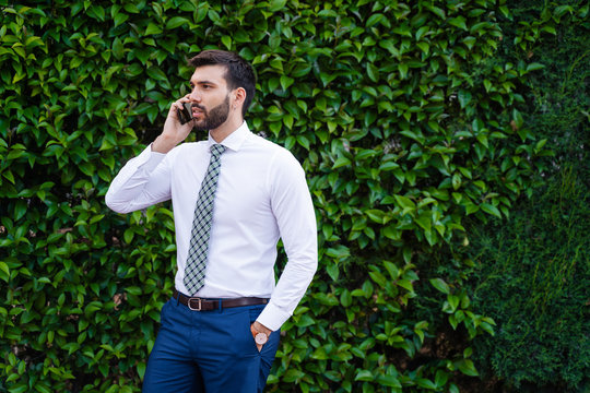 Young Business Man With White Shirt And Tie In Outdoor Park Making Phone Call