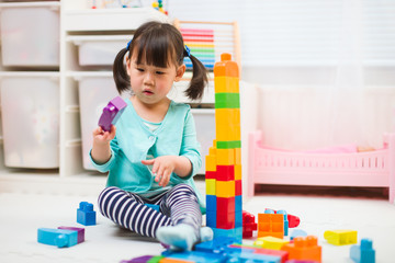 toddler girl playing creative toy blocks at home