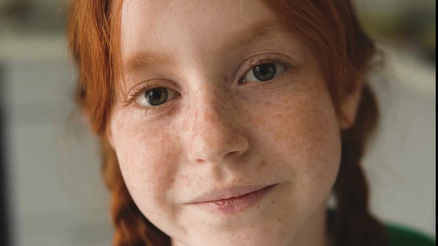 Charming red haired girl looking at camera smiling. Closeup lovely sweety child&nbsp;