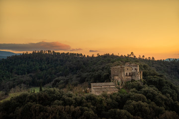 Fototapeta na wymiar Medieval Spanish castle in forest with setting sun creating a firey yellow sky.