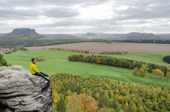 Deutschland, Sachsen, S&auml;chsische Schweiz, Wanderung von Wehlen &uuml;ber die Rauensteine, Wanderer sitzt am Felsen &uuml;ber dem Abhang, Blick von den Rauensteinen auf den Lilienstein