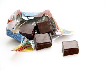 Chocolate broken blocks coming out an open wrapper with foil