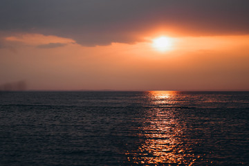 Beautiful orange sunset or sunrise near seaside ocean dark colors
