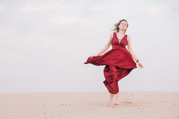 Girl in red dress at sunset in the desert