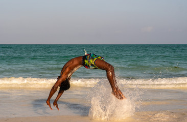 Young Attractive Muscular and Strong Athletic Black African Man at the White Sand Beach Training Acrobatics and Jumping Gymnastics Beach Performance
